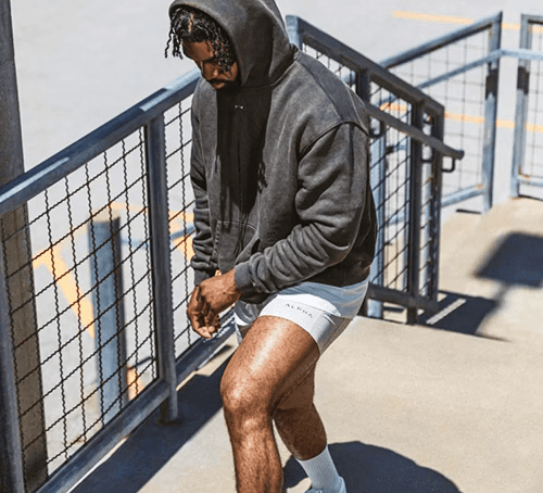 man walking up stairs wearing a grey hoodie from alpha industries