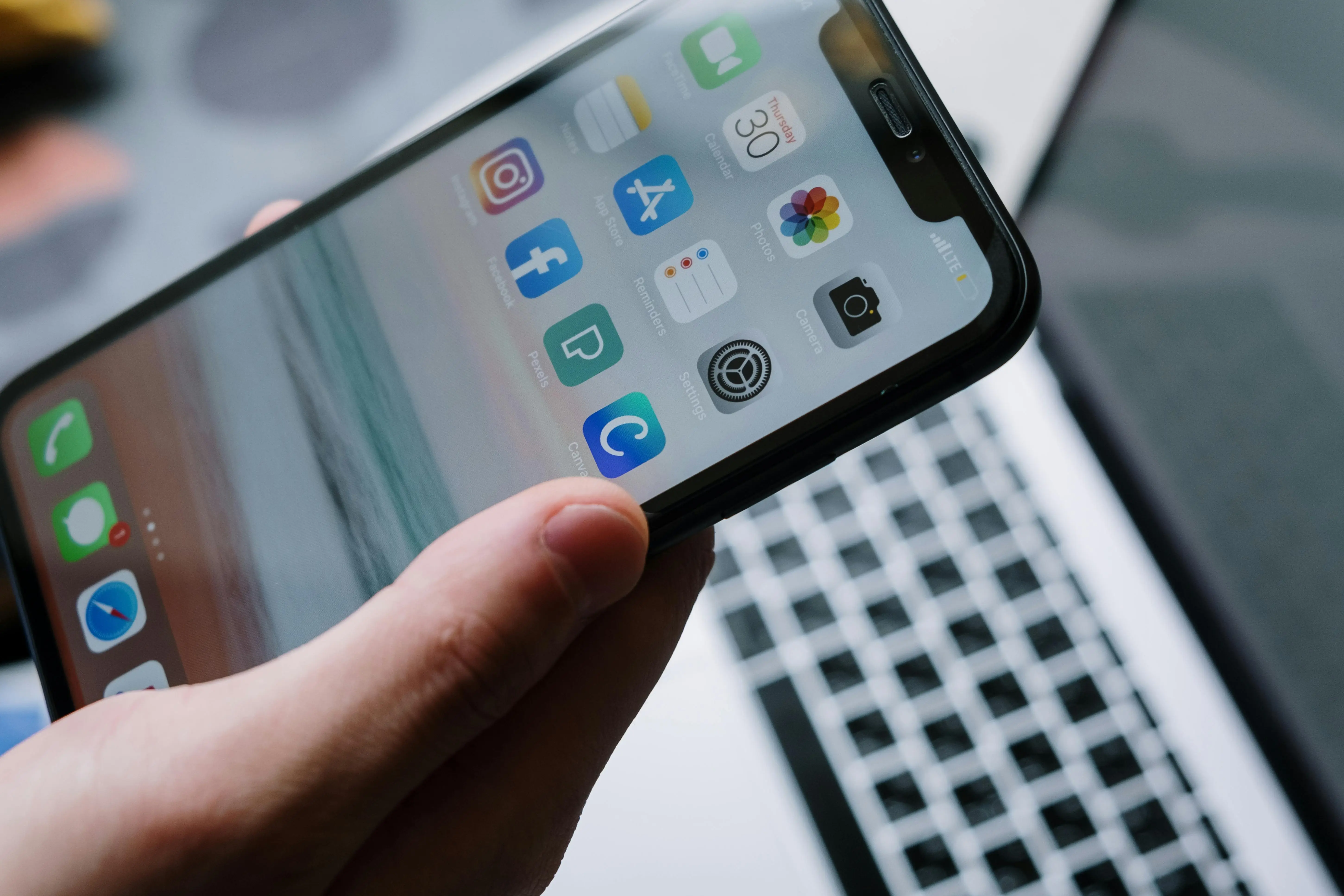 Pantalla de smartphone con aplicaciones encima de un teclado de laptop